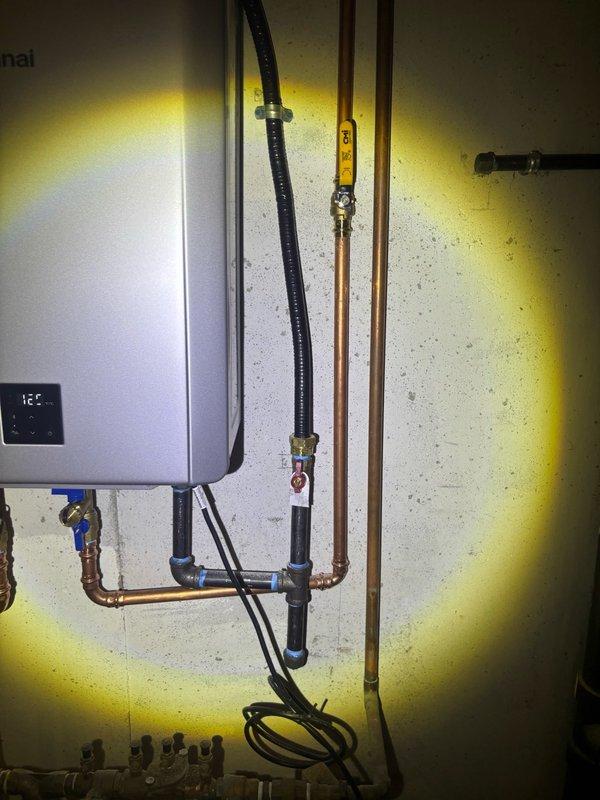 Documented tankless water heater installation by photographing the Rinnai unit and associated plumbing connections, including serial number and system components as requested. The unit displayed operational status with digital readout showing 321, and all copper supply lines, gas connections, shut-off valves, and manifold fittings were captured for service records.