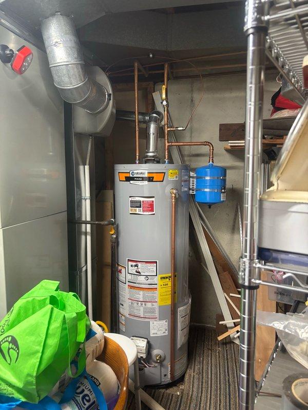 Documented newly installed State ProLine+ commercial-grade water heater by photographing serial number plate and installation details per service request. Verified proper installation including copper piping connections, expansion tank mounting, gas shutoff valve accessibility, and venting configuration.