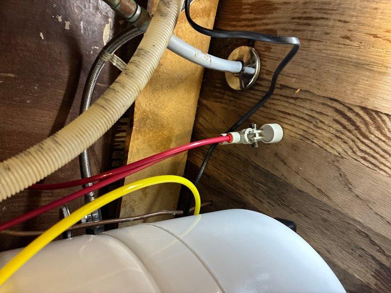 Replaced water filter system under kitchen sink. Removed existing filtration unit and installed new system including white cylindrical storage tank, filtration housing, and associated plumbing connections. Connected supply lines using PVC piping, brass fittings, and flexible hoses with proper clamps and seals. Routed electrical wiring for system operation and verified all connections for proper function and leak-free operation.