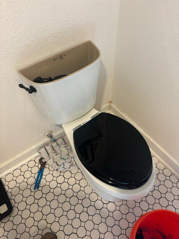 Responded to reported toilet leak in bathroom. Upon arrival, diagnosed faulty angle stop valve supplying water to toilet fixture. Shut off main water supply and removed defective chrome-plated angle stop valve showing mineral deposits and signs of deterioration at compression fittings. Replaced valve with new unit, ensuring proper thread seal and compression connections. Removed toilet tank lid to inspect internal flush mechanism for additional leak sources. Verified all tank components functioning properly with no signs of internal leakage. Reinstalled hardware, restored water supply, and tested system under full pressure to confirm complete resolution of leak. All connections verified watertight with no visible dripping or seepage detected.
