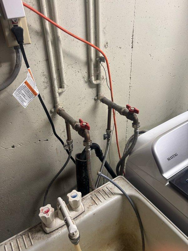 Responded to reported water leak in basement. Upon inspection, identified leak originating from plumbing connections mounted to wall near water heater and laundry appliances. Repaired faulty pipe fittings secured with rubber grommets, tightened hex nut connections on braided flex line, and verified integrity of PVC pipe connections. Tested all repaired connections under pressure to confirm leak was resolved. System restored to proper working condition with no active leaks detected.