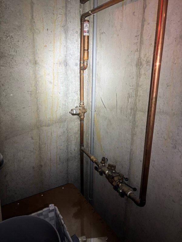 Responded to plumbing maintenance call for leaking kitchen faucet and two exterior hose bibs. Inspected basement plumbing infrastructure including copper supply lines and brass shutoff valves serving the affected fixtures. Assessed water heater systems and related piping connections. Evaluated exterior spigot conditions and identified sources of leakage requiring repair. Verified proper operation of basement shutoff valves and examined water supply distribution system. Documented existing plumbing conditions with photographic evidence showing copper piping installation, brass valve assemblies, and water treatment system maintenance area. Provided recommendations for necessary repairs to eliminate leaks at kitchen faucet and outdoor hose connections.