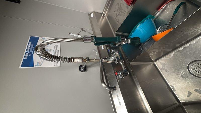 Conducted site assessment for commercial kitchen plumbing reconfiguration project involving relocation of freestanding sink assembly with existing pre-rinse spray valve system. Evaluated current plumbing infrastructure including supply lines, drainage connections, and mounting requirements for repositioning commercial-grade stainless steel basin unit. Documented existing fixture conditions including pre-rinse spray assembly with coiled hose, assessed replacement needs for faucets, spray valves, and drain components to prepare comprehensive estimate for plumbing modifications and new fixture installations.