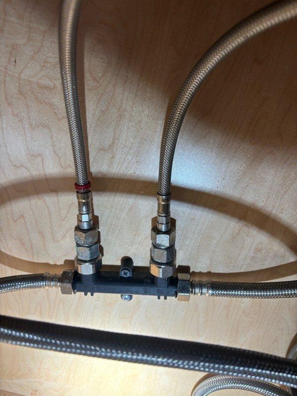 Conducted comprehensive inspection of whole home water conditioning system in response to reports of black grit contamination found in washing machine inlet filter. Examined under-sink plumbing assembly including manifold distribution system with braided stainless steel supply lines and compression fittings to assess potential sources of sediment. Inspected all visible plumbing connections, supply hoses, and water distribution points for signs of deterioration, corrosion, or debris accumulation that could contribute to particulate contamination in downstream fixtures. Evaluated kitchen sink installation and water delivery system to determine if conditioning equipment requires maintenance or replacement. Prepared detailed estimate for installation of dedicated hot water return line to accommodate tankless water heater recirculating pump system, including assessment of existing plumbing layout, routing requirements, and necessary materials for proper circulation loop implementation.