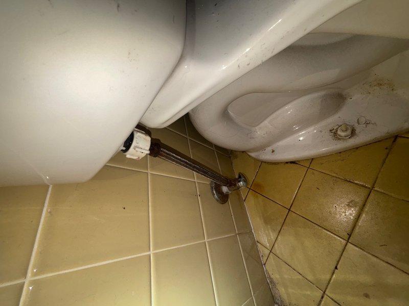 Responded to reported water supply line leak at toilet fixture in main hallway bathroom. Upon arrival, inspected the chrome water supply line connection between the wall shut-off valve and toilet tank fill valve. Identified leak source at the supply line connection point. Replaced the existing water supply line with new flexible stainless steel braided supply line. Installed new connection hardware at both the shut-off valve and toilet tank fill valve to ensure proper seal. Tested system by turning water supply back on and cycling toilet multiple times to verify leak was eliminated and all connections were secure with no water seepage.