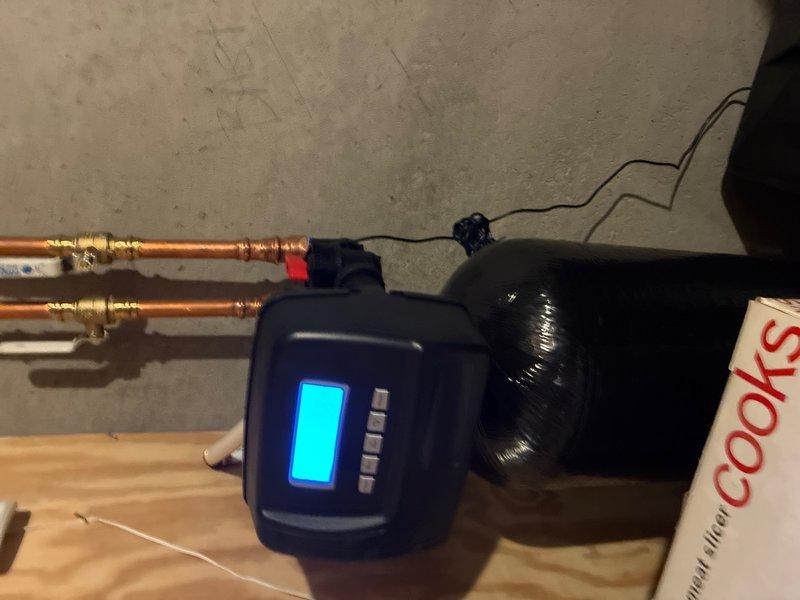 Responded to service call for non-functioning water softener system in basement. Performed diagnostic testing of water quality using test strips to measure chlorine and mineral levels, then inspected the water treatment system including digital control valve and brine tank. Verified proper operation of equipment, checked electrical connections, and confirmed system settings on the digital display panel were correctly programmed for optimal water conditioning performance.