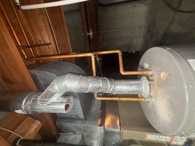 Responded to no hot water complaint affecting entire residence. Upon inspection, found tanked water heater in basement with failed heating element. Diagnosed and replaced defective lower heating element and tested upper element for proper operation. Flushed sediment buildup from tank bottom to improve heating efficiency and prevent future element failure. Inspected all plumbing connections, copper supply lines, and venting system for proper operation and code compliance. Verified temperature and pressure relief valve functionality and checked for any signs of leakage around tank base and connections. Restored hot water to full household operation and confirmed proper temperature settings on thermostat. Exterior drainage system inspected and found operational with no plumbing-related concerns. Unit tested successfully with hot water delivery confirmed throughout residence.
