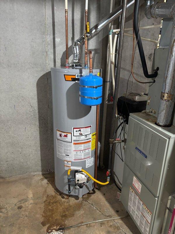 Completed installation of a 50-gallon gas-fired water heater in basement utility area. Unit was positioned on concrete floor and connected to existing gas supply line using flexible yellow connector for code compliance. Installed copper supply piping to top of unit along with thermal expansion tank mounted on cold water inlet line to protect against pressure buildup in closed plumbing system. Connected proper venting using black plastic piping routed upward for exhaust gases. Verified all gas connections for leaks, tested temperature and pressure relief valve operation, and confirmed proper water flow through hot water distribution system. Installation meets current plumbing codes and manufacturer specifications.
