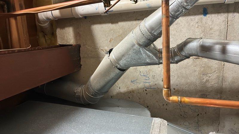 Responded to a no hot water emergency call where both water heater pilot lights had extinguished and a strong burnt wood odor was detected during relight attempts. Gas supply to both units had been shut off as a safety precaution. Conducted a thorough inspection of both water heaters located in the basement, examining the burner assemblies, pilot light assemblies, thermocouples, and gas control valves for signs of malfunction or damage. Assessed the venting system and flue pipes for proper draft and blockages that could cause combustion odors. Checked for gas leaks at all connections and verified proper ventilation in the mechanical room. Documented the condition of both units with photographic evidence showing the basement plumbing infrastructure, copper supply lines, and utility area layout. Provided estimate for necessary repairs or replacement based on findings from the diagnostic inspection.