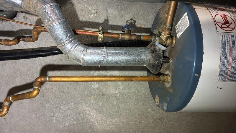 Conducted on-site evaluation of 30-year-old gas water heater located in basement to provide replacement estimate. Inspected existing 40-gallon Rheem gas unit with standard copper piping connections, brass shutoff valves, and galvanized venting system. Unit currently operational but at end of service life. Assessed plumbing configuration including hot and cold water lines with shutoff valve, pressure relief valve connections, and gas line setup. Reviewed system pressure via mounted gauge reading approximately 20 PSI. Documented existing installation including copper supply lines with natural patina, flexible gas connector, and concrete floor mounting location. Provided comprehensive estimate for replacement with new 40-gallon gas water heater including necessary connections, venting, and code-compliant installation.