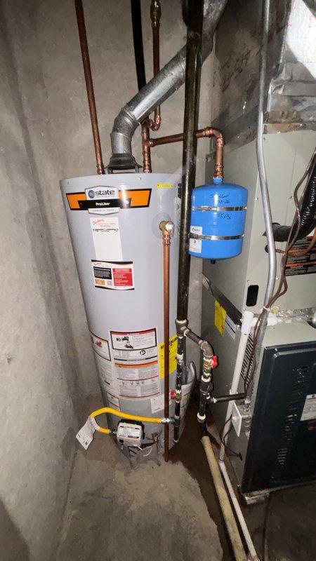 Installed a new 40-gallon State brand gas water heater in the basement mechanical room, complete with proper venting through metallic duct work and elbow joint. Added a thermal expansion tank (blue pressure tank) mounted to the wall and integrated into the plumbing system via copper piping. Connected water heater to existing gas line using yellow flexible gas connector, installed pressure monitoring gauge with dual PSI/KPa measurement capability, and ensured all copper water supply lines were properly connected to both the new water heater and expansion tank for optimal system performance and pressure regulation.