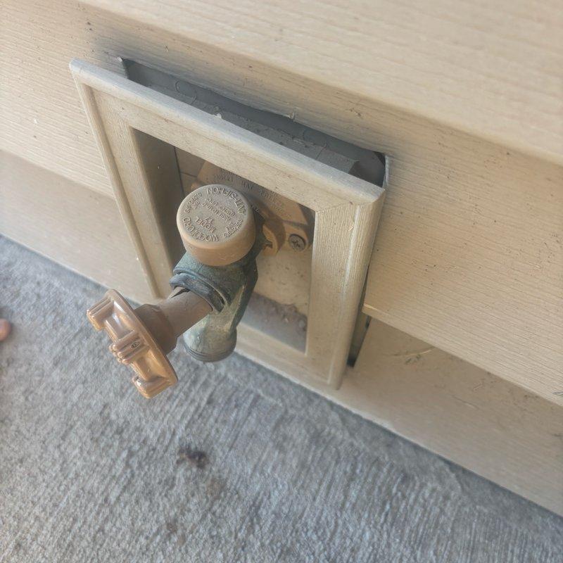 Completed plumbing estimate for residential backyard project involving gas line installation from basement to outdoor firepit area for patio construction, with potential coordination for pool company gas line connection. Assessed and documented existing hose bib with bent valve mounted in recessed exterior outlet box on building siding, recommending replacement due to compromised condition. Evaluated copper piping showing weather-related corrosion and patina, photographed installation points including side yard access area near basement window for project planning purposes.