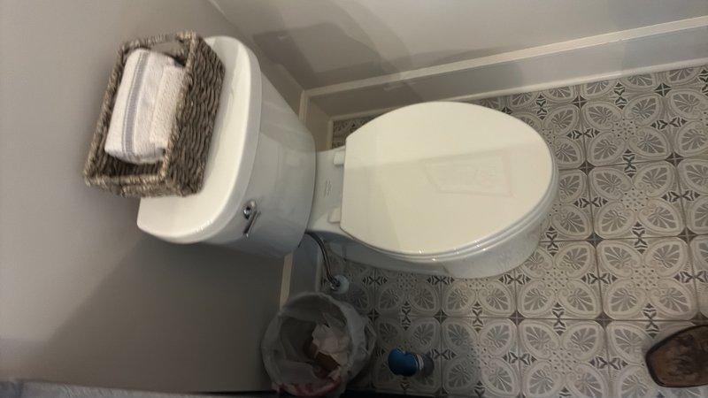 Responded to guest bathroom for customer-provided toilet installation. Removed existing toilet fixture, including disconnection of water supply line and wax ring removal. Prepared flange and floor surface for new installation. Set new toilet unit with fresh wax ring seal, ensuring proper alignment with floor flange and decorative tile pattern. Connected braided stainless steel supply line to fill valve and shut-off valve. Secured toilet to floor with closet bolts and tested for proper seating. Turned on water supply, filled tank, and performed multiple flush cycles to verify proper operation and check for leaks at supply connection, tank-to-bowl seal, and base. Confirmed stable installation and no water seepage. Installation completed successfully with all connections secure and fixture functioning properly.