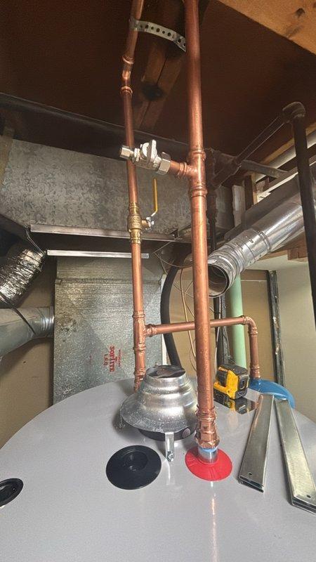 Completed installation of a 50-gallon gas water heater with thermal expansion tank in residential utility space. Installed new copper supply piping with appropriate shutoff valves, pressure relief valve, and gas line connections. Mounted thermal expansion tank to protect against system pressure buildup caused by water thermal expansion. Secured all piping to wall framing with proper brackets and hangers, ensuring code-compliant clearances around unit. Verified proper venting connections and tested all gas connections for leaks. System was filled, purged of air, and test-fired to confirm proper ignition and operation. All connections were inspected for leaks and unit was left in full operational condition.