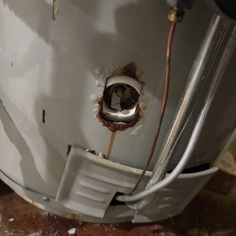 Responded to emergency service call for water heater with blown gasket. Upon arrival, water supply had already been shut off by customer to prevent further flooding. Inspection revealed significant internal corrosion and rust accumulation around the tank base and drain assembly, indicating advanced deterioration of the unit. The pressure tank system showed external condensation and corroded copper piping connections, suggesting ongoing moisture issues within the plumbing system. Assessed the extent of damage to determine whether gasket replacement was viable or if full unit replacement would be required due to the severity of internal corrosion observed at the tank bottom and drainage components.