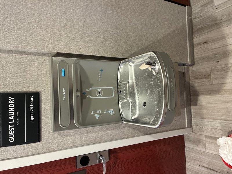 Removed existing drinking fountain and installed new Elkay wall-mounted combination unit featuring both bottle filler station and traditional drinking fountain in guest laundry area. Connected water supply lines, drainage piping including white PVC with appropriate fittings, and installed shutoff valve assembly to mechanical system. Tested all connections for leaks and verified proper operation of both bottle filling sensor and drinking fountain basin.