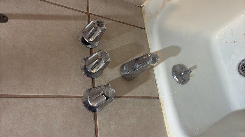Responded to emergency plumbing call for severe leak from three-handle shower valve assembly in upstairs bathroom that required shutting off water supply to entire house. Removed existing three-handle shower trim and valve stems, assessed wall cavity for water damage, and converted system to modern single-handle pressure-balancing valve. Installed new single-handle trim kit with chrome finish, tested for proper operation and leak-free connections, and restored water service to residence.