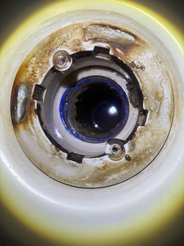 Responded to report of slow leak at master bathroom shower drain. Accessed plumbing system from basement below to inspect drain lines and connections. Upon investigation, discovered significant water staining and corrosion around shower drain assembly, indicating prolonged moisture exposure. Inspected PVC drain piping running through floor joists and confirmed leak origin at drain flange connection. Documented existing conditions showing deteriorated drain seal and mineral buildup on drain components. Provided assessment of leak source and recommended repair options to address compromised drain assembly and prevent further water damage to structure.