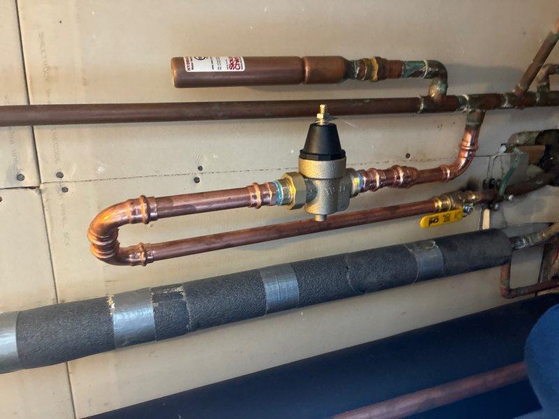 Installed new 3/4" pressure reducing valve (PRV) on main water line. Removed existing main shut off valve that was positioned too close to the whole-house water supply tee, preventing proper PRV installation. Installed new ball valve in upward-facing orientation to accommodate PRV assembly. Rerouted and repiped copper water line from new PRV back into main supply line feeding the house, ensuring proper water pressure regulation throughout the system.