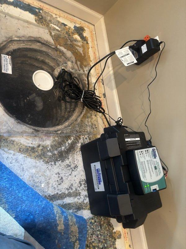 Installed Watchdog sump pump system in basement location with existing basin showing signs of water damage and mineral deposits. Primary installation included 1/2 HP energy efficient permanent split capacitor (PSC) pump with capacity of 4,400 GPH at 0 ft. lift and 3,540 GPH at 10 ft. lift, along with battery backup system providing 2,500 GPH at 0 ft. lift and 1,850 GPH at 10 ft. lift. Configured float mechanism, connected electrical components including backup battery unit, and verified proper operation of dual pump system to provide reliable water removal and emergency backup protection.