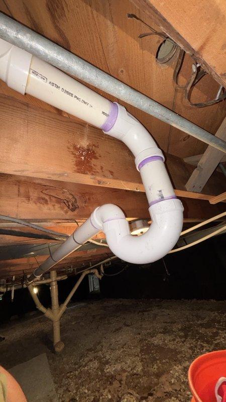 Installed a new 1-1/2" P-trap assembly on PVC drain line for shower in crawl space beneath residence. Connected trap using purple-primed couplings to existing drain system, ensuring proper drainage slope and secure watertight connections per plumbing code requirements.