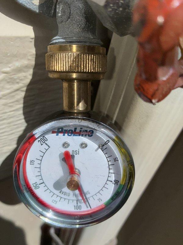 Performed plumbing system inspection and pressure monitoring on residential water supply system. Verified system pressure reading at approximately 200 PSI on ProLine pressure gauge mounted to brass pressure regulator assembly, which exceeds typical residential operating range of 40-80 PSI. Documented equipment condition and photographed gauge readings for maintenance records.