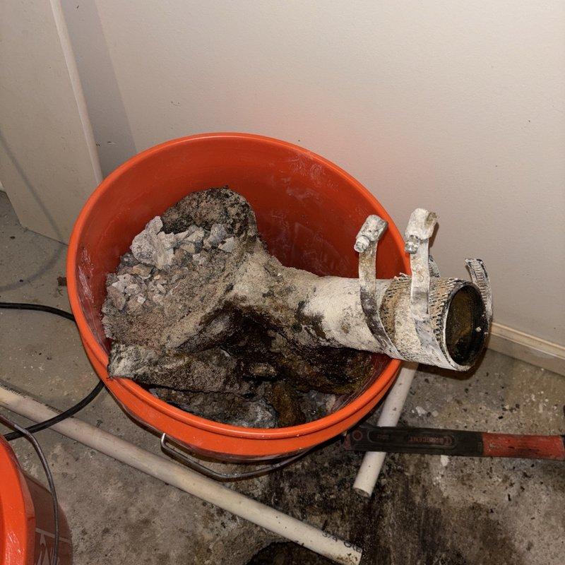 Removed existing deteriorated floor drain showing severe corrosion and mineral buildup from utility room concrete floor. Installed new floor drain assembly equipped with integral check valve to prevent backflow and sewage backup. Completed piping connections and tested drainage system for proper operation and seal integrity.