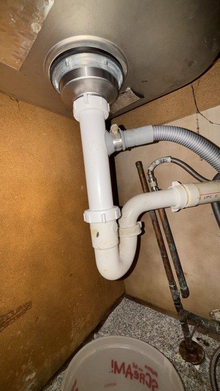 Responded to service call for broken pipe under kitchen sink. Upon arrival, inspected the cabinet area and identified damaged drain assembly requiring replacement. Removed existing P-trap configuration and drain tailpiece. Installed new brass drain tailpiece and white PVC P-trap assembly with proper threaded connections. Verified all slip-joint connections were properly sealed and tightened to manufacturer specifications. Tested drainage system for leaks and confirmed proper water flow. Cleaned work area and removed debris from cabinet space.