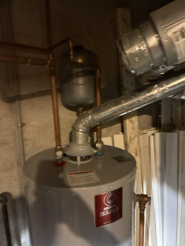 Responded to complaint of sewer odor in upper bedroom. Conducted thorough inspection of plumbing system including water heater, supply lines, and accessible plumbing connections. Inspected wall-mounted plumbing access panel containing hot and cold water shut-off valves with braided supply lines. Examined basement mechanical room plumbing infrastructure including water heater connections, copper piping, expansion tank, and associated shut-off valves. Documented existing plumbing configuration with photos for reference. Unable to identify definitive source of sewer gas odor during this visit; recommend further investigation of drain traps, vent stack system, and wax ring seals at toilet fixtures in upper level to isolate odor source.