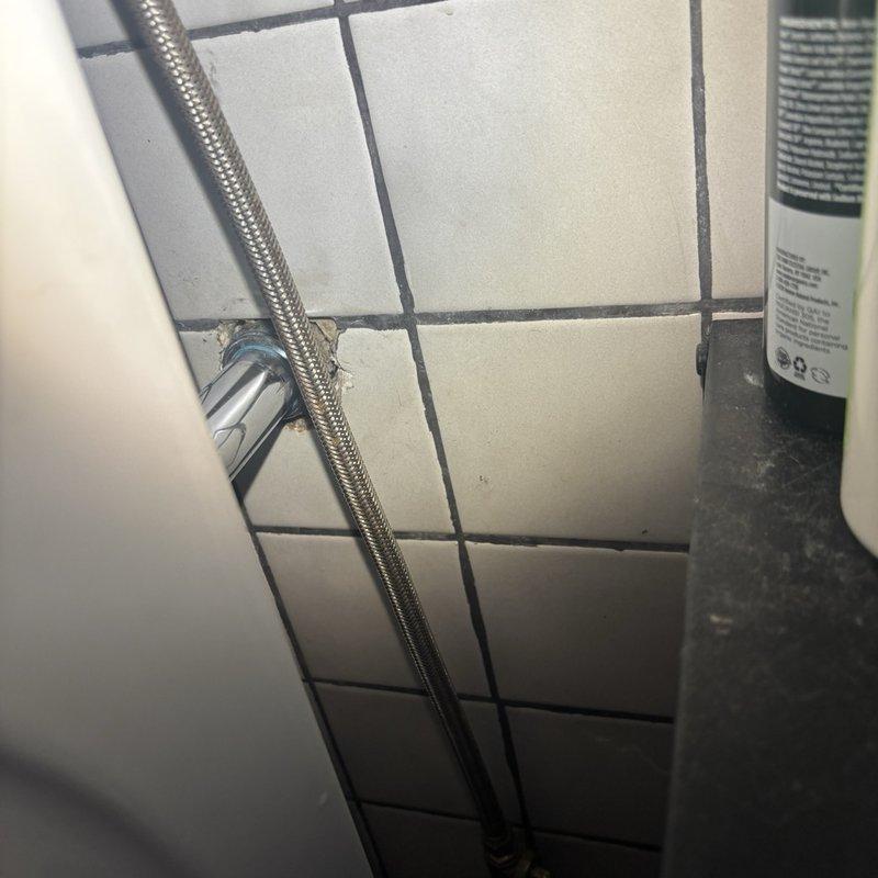 Responded to callback for persistent leak at bathroom sink originally addressed on previous visit. Upon inspection, accessed plumbing behind wall cavity and identified leak source at vertical drain assembly. Leak was caused by compromised connection points on black PVC drain pipe secured with metal hose clamps. Tightened all clamp connections on the vertical waste assembly and horizontal branch lines, inspected flexible supply line connections at wall-mounted fixture, and verified proper seal at all joints. Tested system under full water pressure to confirm leak resolution. Wall access opening left available for final verification before closure.