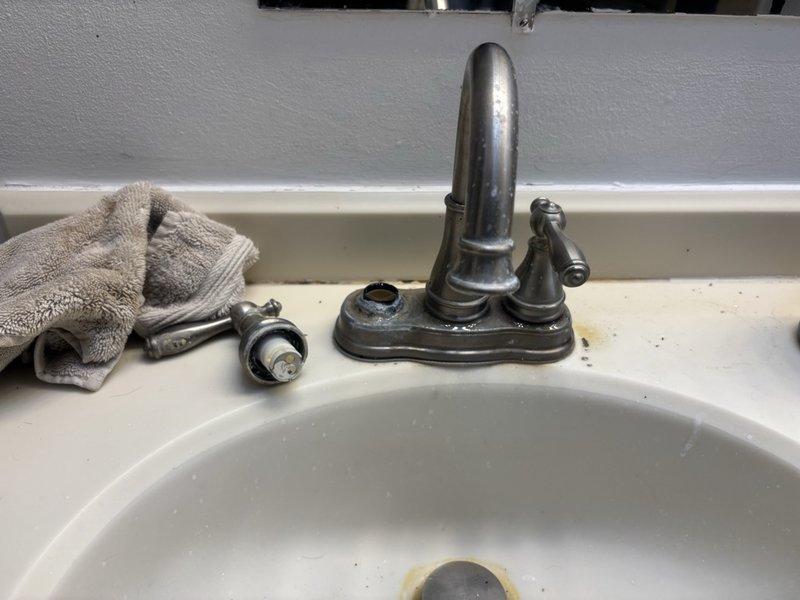 Responded to leak locate service call for main bathroom sink with broken knob causing water intrusion into basement below. Upon inspection, found faucet assembly compromised with damaged handle mechanism leading to active leak at supply connections. Disassembled faucet components to assess extent of damage and trace leak path through floor assembly. Located source of water penetration at deteriorated supply line connections beneath vanity cabinet. Inspected basement ceiling area directly below fixture and identified water damage along copper supply piping and flexible supply hoses. Documented condition of faucet hardware, supply connections, and affected piping infrastructure. Provided assessment of necessary repairs including faucet replacement and potential supply line service to resolve leak and prevent further water damage.
