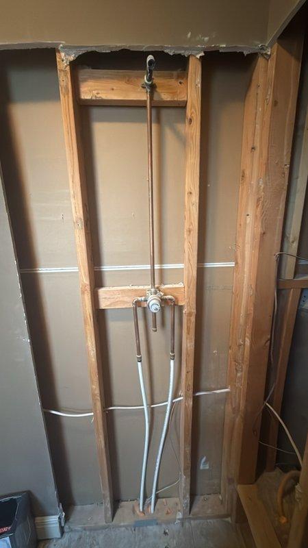 Replaced defective shower valve in main floor bathroom. Removed section of drywall to access existing plumbing assembly behind wall studs. Disconnected old mixing valve from copper supply lines and installed new valve assembly, ensuring proper connections to hot and cold water supplies and connection to shower head outlet. Tested new valve for proper operation and verified no leaks at all connection points.