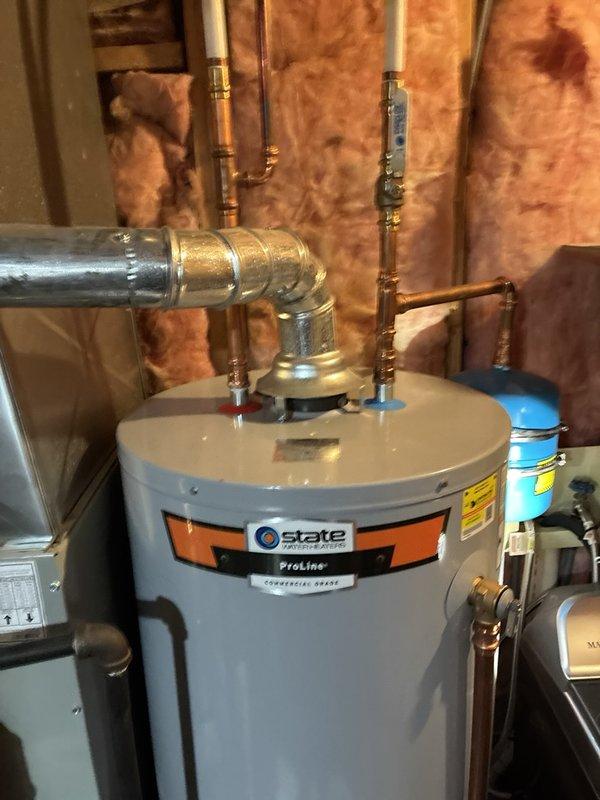 Performed plumbing inspection of basement utility area and water heater installation. Documented existing State ProLine water heater with copper and galvanized piping connections, expansion tank, and exposed plumbing infrastructure in unfinished space with proper insulation present between wall studs.