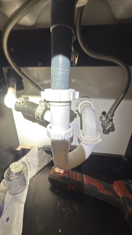 Responded to follow-up service call for broken drain pipe under sink that was damaged during previous HVAC service visit. Upon inspection, discovered that a 1.5-inch PVC drain pipe nipple connected to the HVAC condensate drain system had broken off inside the wall assembly while attempting to clear a clog from the vinyl drain attachment. Assessed repair options and determined that accessing the broken section would require cutting into the drywall behind the cabinet to properly reattach the drain connection. Obtained approval to proceed with necessary drywall work to complete the repair. Replaced the damaged 1.5-inch drain section and reconnected the HVAC condensate drain line to the new P-trap assembly, ensuring proper drainage function for both the sink and HVAC system. All work was completed at no charge as the damage originated from the previous HVAC service visit.