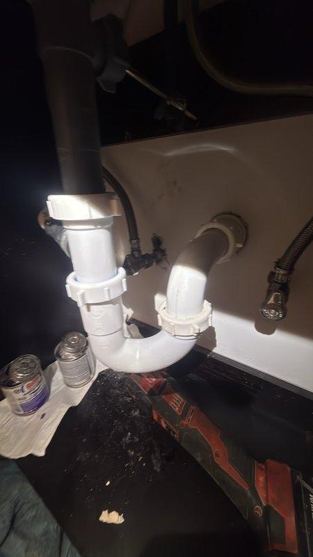 Responded to follow-up service call for broken drain pipe under sink that was damaged during previous HVAC service visit. Upon inspection, discovered that a 1.5-inch PVC drain pipe nipple connected to the HVAC condensate drain system had broken off inside the wall assembly while attempting to clear a clog from the vinyl drain attachment. Assessed repair options and determined that accessing the broken section would require cutting into the drywall behind the cabinet to properly reattach the drain connection. Obtained approval to proceed with necessary drywall work to complete the repair. Replaced the damaged 1.5-inch drain section and reconnected the HVAC condensate drain line to the new P-trap assembly, ensuring proper drainage function for both the sink and HVAC system. All work was completed at no charge as the damage originated from the previous HVAC service visit.