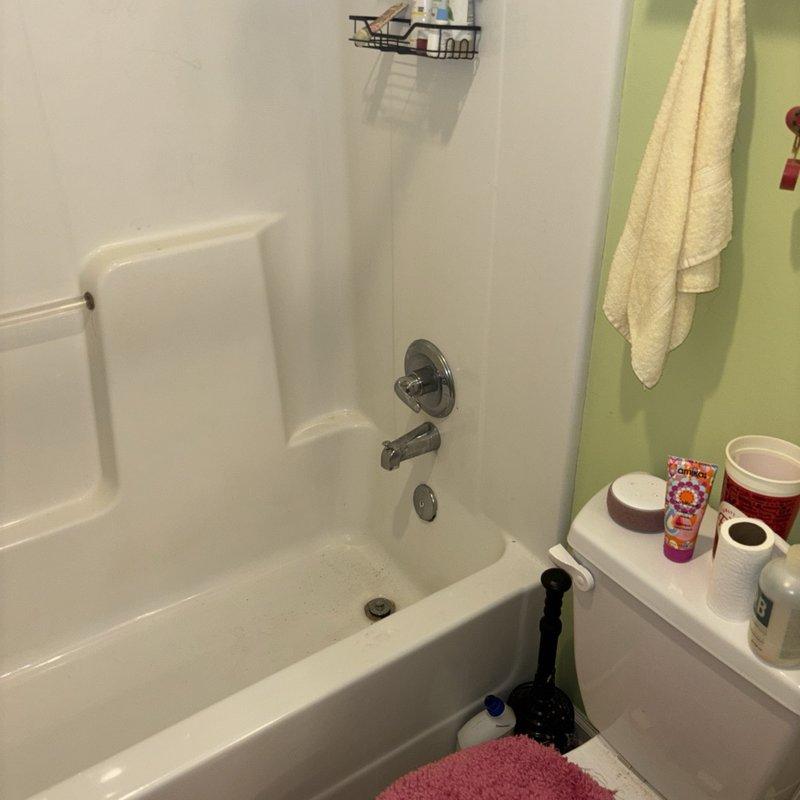 Responded to service call for inoperable shower diverter in main bathroom. Upon arrival, found chrome bathtub spout with stuck diverter knob preventing shower activation. Inspection revealed significant calcium and mineral deposit buildup on spout fixture due to hard water accumulation, which was causing mechanical binding of the diverter mechanism. Documented existing condition showing heavy white crusty deposits concentrated on chrome spout surface. Assessed shower/tub combination unit with standard white porcelain finish and chrome fixtures for repair recommendations.