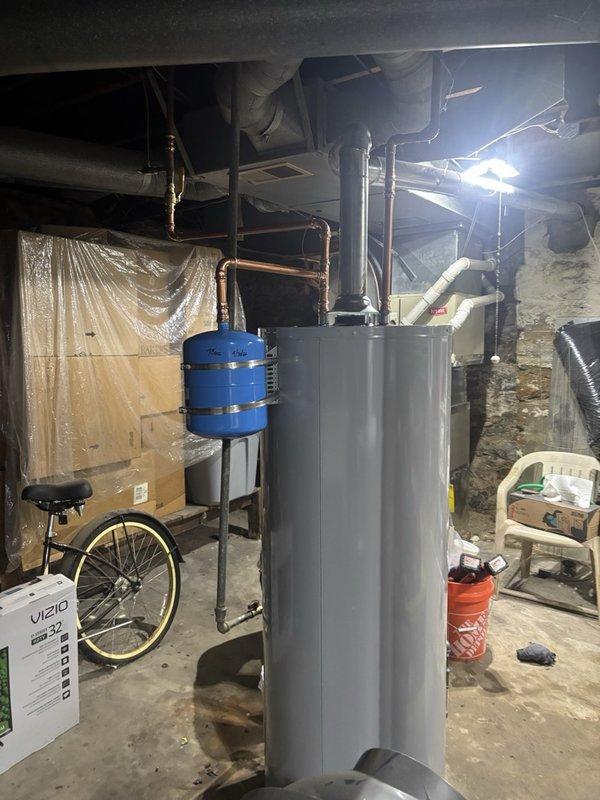 Completed installation of a 50-gallon gas-fired water heater in basement utility area. Installed thermal expansion tank on cold water supply line to protect against pressure fluctuations and comply with plumbing code requirements. Connected all copper supply piping with appropriate shut-off valves, established proper venting for gas appliance, and tested system for leaks and proper operation upon completion.