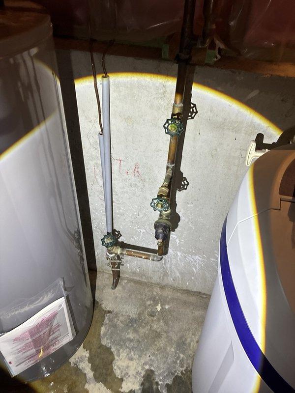 Responded to service call for 50-gallon electric water heater showing signs of leaking in basement location. Upon inspection, documented existing unit under 10 years old with visible water staining on concrete floor surrounding equipment. Assessed plumbing configuration including copper piping, shut-off valves, and connections between water heater and auxiliary tank. Provided estimate for replacement of leaking 50-gallon electric water heater with comparable capacity unit, maintaining existing electrical and plumbing connections.