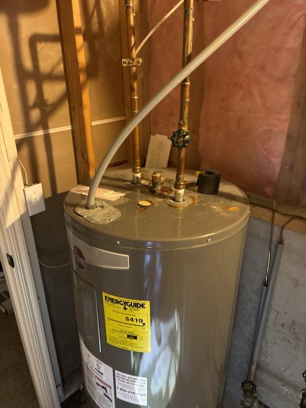 Responded to service call for 50-gallon electric water heater showing signs of leaking in basement location. Upon inspection, documented existing unit under 10 years old with visible water staining on concrete floor surrounding equipment. Assessed plumbing configuration including copper piping, shut-off valves, and connections between water heater and auxiliary tank. Provided estimate for replacement of leaking 50-gallon electric water heater with comparable capacity unit, maintaining existing electrical and plumbing connections.