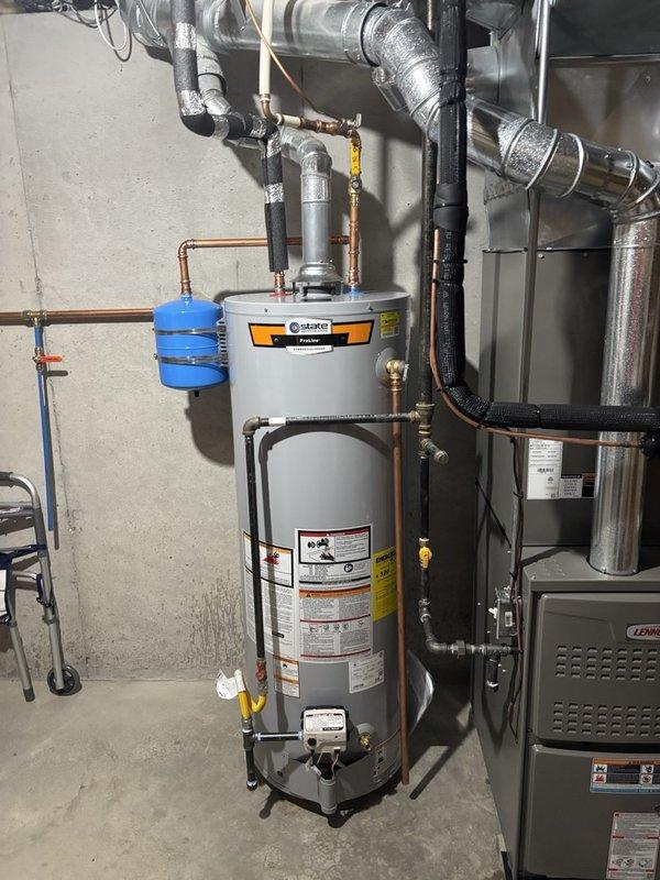 Completed installation of a 40-gallon gas water heater in basement utility area with integrated thermal expansion tank system. Installed blue expansion tank on wall with proper copper piping connections, ensuring correct pressure relief configuration. Routed and connected all hot and cold water supply lines using copper pipe with brass fittings, installed gas supply line with appropriate shutoff valve, and verified all connections for proper operation and code compliance.