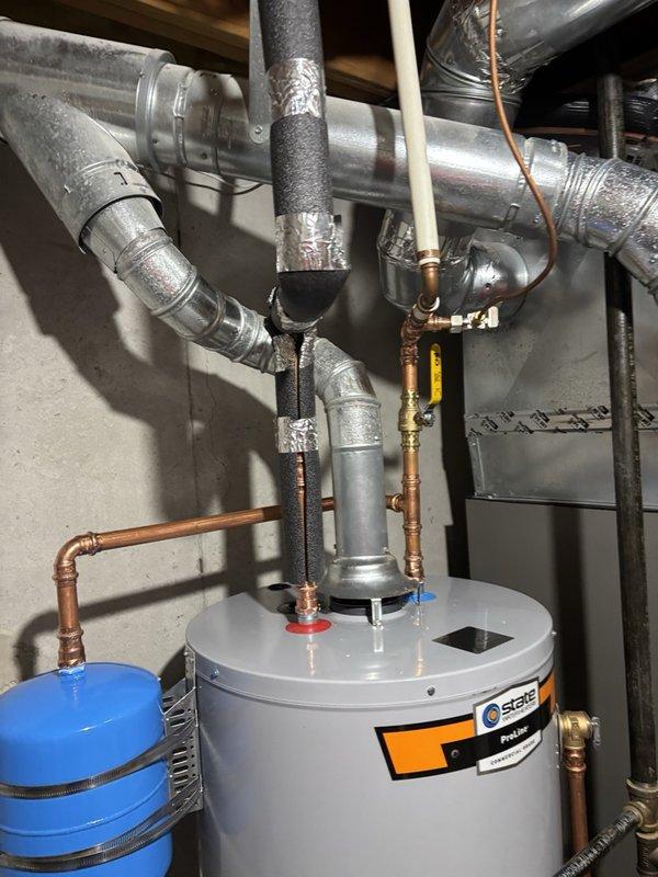 Completed installation of a 40-gallon gas water heater in basement utility area with integrated thermal expansion tank system. Installed blue expansion tank on wall with proper copper piping connections, ensuring correct pressure relief configuration. Routed and connected all hot and cold water supply lines using copper pipe with brass fittings, installed gas supply line with appropriate shutoff valve, and verified all connections for proper operation and code compliance.