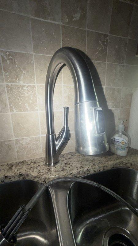 Installed customer-supplied chrome pull-down kitchen faucet with detachable spray head on dual-basin sink with granite countertop. Additionally, installed new single-handle shower valve. Under-sink plumbing connections completed with proper P-trap configuration using white PVC piping, ensuring secure drainage and code-compliant installation.
