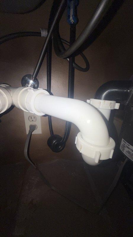 Installed customer-supplied chrome pull-down kitchen faucet with detachable spray head on dual-basin sink with granite countertop. Additionally, installed new single-handle shower valve. Under-sink plumbing connections completed with proper P-trap configuration using white PVC piping, ensuring secure drainage and code-compliant installation.
