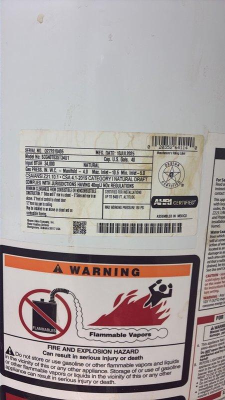 Conducted comprehensive piping assessment for water heater replacement and associated plumbing connections. Documented existing natural gas water heater unit (Model GCVAH03511401) manufactured in August 2019, noting ASME certification and current condition. Evaluated deteriorated copper piping system showing extensive corrosion, white and green oxidation buildup, and mineral deposits indicating prolonged moisture exposure. Inspected HVAC integration points where copper lines interface with heating components and coil assemblies. Photographed corroded pipe sections requiring replacement to prevent potential leaks and system failures. Assessed surrounding infrastructure including fiberglass insulation and structural mounting conditions to determine scope of piping modifications needed for new installation.