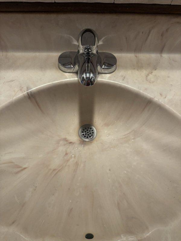 Successfully installed two faucets as requested: one in the bathroom and one in the kitchen. The bathroom installation involved mounting a contemporary chrome three-piece faucet assembly with center spout and dual wing-style handles onto a white marble vanity countertop. The kitchen installation included connecting a new faucet to existing supply lines with braided stainless steel flexible hoses and shut-off valves with red handles beneath the sink. Both installations were completed with proper connections to water supply lines and tested for leaks and proper operation.