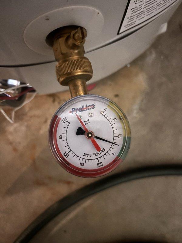 Performed routine plumbing maintenance inspection on DEFENDER Energy System water heater installation. Documented current system conditions including proper venting configuration with metallic exhaust pipe, copper supply line connections, pressure relief valve piping, and white expansion tank mounted on inlet piping. Verified and recorded pressure gauge readings on ProLine gauge showing system operating within normal parameters.