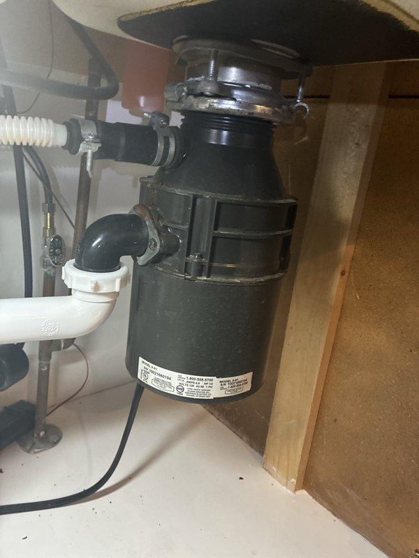 Responded to service call for garbage disposal unit emitting burning smell and failing to operate. Upon inspection, identified failed motor in existing black disposal unit mounted under kitchen sink. Disconnected electrical supply and plumbing connections including drain lines and dishwasher discharge hose. Removed defective disposal unit from sink mounting assembly. Installed new garbage disposal unit, reconnected all plumbing components including P-trap and drain lines, and restored electrical connection. Tested unit for proper operation, verified no leaks at connections, and confirmed normal function without burning odor.