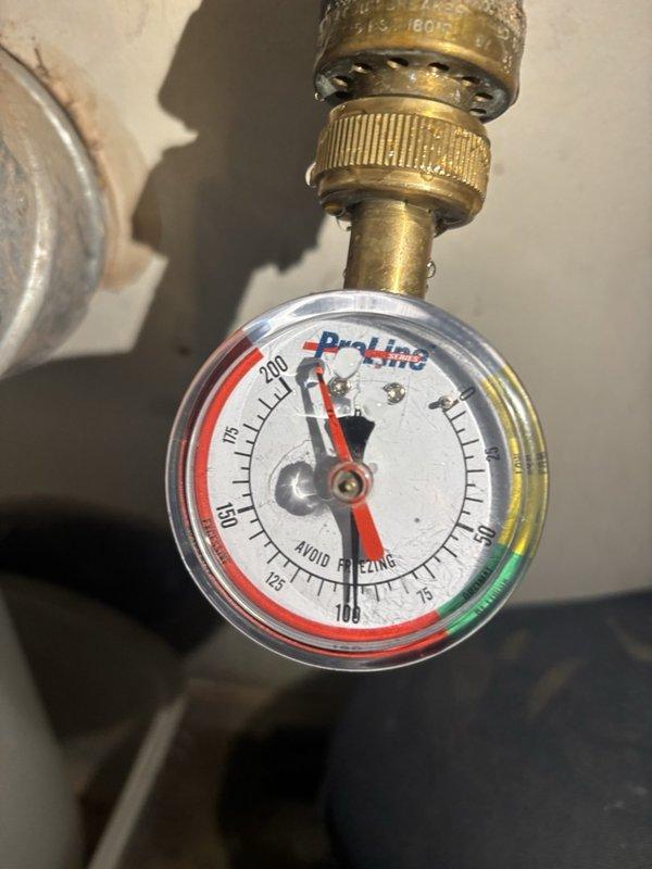 Completed comprehensive plumbing inspection of water pressure monitoring system in utility area. Documented ProLine pressure gauge readings showing approximately 180 PSI on brass fittings connected to water supply line, with gauge displaying proper functionality and clear zone indicators. All connections, brass fittings, and valve assemblies were inspected and photographed for service records.