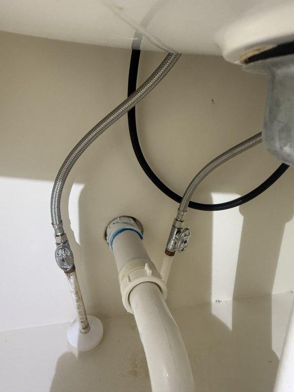 Installed customer-supplied faucet for kitchen sink, connecting braided stainless steel flexible supply lines to water supply valves and securing all connections with appropriate fittings. Completed drain assembly installation with white PVC tailpiece and P-trap configuration, ensuring proper alignment and watertight seals. Verified all supply line connections for leaks, tested faucet operation, and confirmed proper drainage flow upon completion.