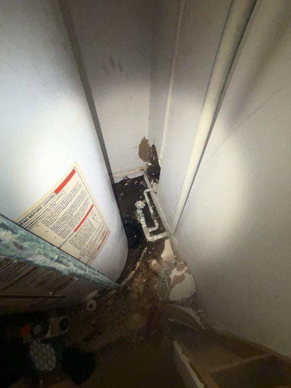Responded to report of water leak in furnace closet extending into hallway. Upon inspection, identified source as Whirlpool water heater with failed connection or component causing water discharge. Documented conditions showing accumulated debris and moisture damage in confined mechanical space between HVAC equipment and wall. Inspected water heater plumbing connections including brass fittings, copper supply lines, and yellow flexible gas line for integrity. Assessed surrounding area for water damage and verified proper drainage. Photographed equipment installation, connection points, and affected areas for service records. Recommended appropriate repairs to resolve active leak and prevent further water intrusion into living space.